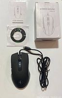 Top view of the black wired mouse, USB cable coiled next to it, with included user manual, setup CD, and product box shown.