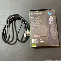 Photo of UltraLink HDMI cable coiled with original box showing 8K Ultra HD and Ethernet capabilities, 5ft length.