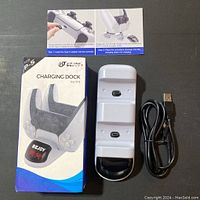 Charging dock with box, dock unit, Type-C USB cable, and instruction pamphlet laid flat on surface.