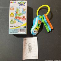 Full view of the Popkey Pals toy car key fob with three tactile keys attached on a yellow ring, accompanied by original packaging and instruction leaflet.