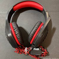Front view of black and red gaming headset with cushioned ear cups and adjustable microphone boom.