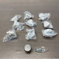 Ten metal dresser knobs individually packaged in plastic.