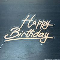 Happy Birthday LED neon light sign unlit on dark wood surface.