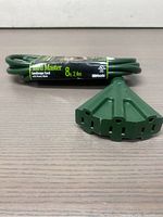 Green Yard Master landscape cord with power block showing the multiple outdoor outlets and the cord coiled with label intact.