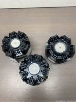 Set of three black LED garage lights showing top with circular LED arrays and folded panels