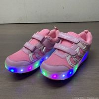 Front angled view of the pink Aimoge roller skate shoes displaying mesh and velcro strap design with glowing multicolor LED lights in the sole.
