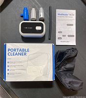 Overview photo showing ozone cleaner device, three nozzle attachments, flexible hose, manual and packaging box