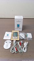 Easy@Home TENS and Muscle Stimulator device and its accessories arranged with box and manual on a wooden surface.