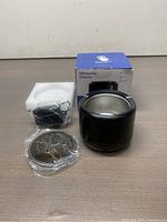 Ultrasonic cleaner main unit, metal tray accessory, power adapter and original box displayed on a surface.