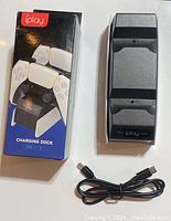 Photo showing the iPlay charging dock, the box packaging with label 'charging dock for PS5,' and the included USB charging cable.