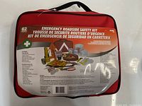 Red emergency roadside safety kit bag with handle, showing product information and included 62 items.