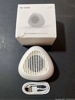 White triangular HE-X002 ultrasonic fruit and vegetable washing machine with slotted vents and USB charging cable in front of seller's box.