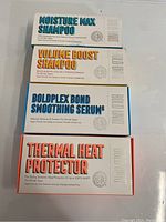 Four boxed hair care products stacked vertically showing brand and product names