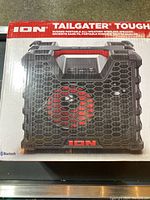 Image of the speaker in its retail box showing the product branding and a photo of the speaker itself.