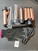 Overview photo of Max-T curling iron set with multiple barrels and protective glove arranged on a surface.