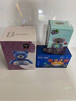 Three boxed kids toys: blue teddy bear sleep soother projector, cute crab light-up music toy, and polar bear soothing animal projector.