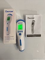 Front view of Derrcom thermometer, box, and instruction manual showing model and LCD screen with reading.