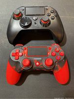 Two wireless gaming controllers with ergonomic grips, one black with red accents and one red and black with glowing red buttons.