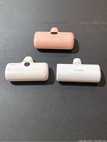 Top view of three Lightning adapter power banks laid on a dark surface showing their built-in connectors and varying colors.