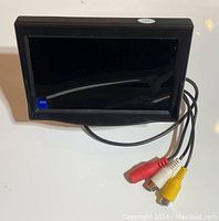 Front view of vehicle rear view screen showing LCD display and red, white, yellow RCA input cables attached.