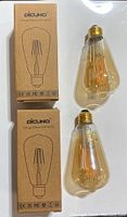 Two vintage Edison LED bulbs shown with their packaging boxes from brand Dicuno, amber tinted glass and exposed filament visible.