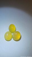 Three natural yellow fire opal cabochons displayed on white background under diffuse lighting to show translucency and surface condition.