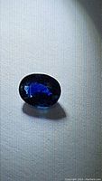 Close-up of deep blue oval cut sapphire showing facets and color under direct light