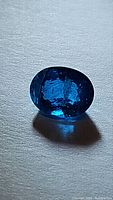 Close-up image of an oval faceted deep paraiba blue apatite gemstone showing rich blue color and clarity characteristics.