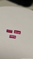 Three rectangular cut pink red untreated natural rubies with transparent clarity and minor inclusions.