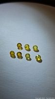 Eight small round yellow sapphires displayed on white background, showing size and color.
