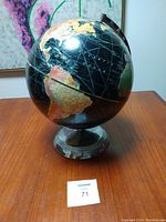 Photo of black globe showing Americas and ocean names on a clear metal base