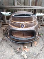 Clay pizza oven dome on metal stand with pizza scraper across top