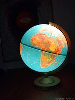 Globe lamp showing detailed map of Africa and surrounding regions, illuminated and mounted on round base with curved arm.