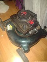 Photo shows a green lawn mower with a black engine cover labeled '3.5' and brand tag 'Legend'. It appears used with some dust and wear.