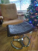 Overall view of footstool positioned in front of a lounge chair and window, showing its shape and proportions