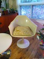 Front view of white fiberglass MCM tulip chair with floral seat cushion.