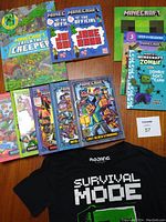 Photo showing all Minecraft books displayed on a wooden surface, along with black Minecraft T-shirt with 'Survival Mode' text visible.