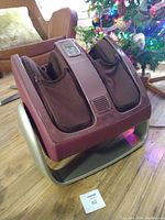 Osim foot massager unit front view showing fabric foot pockets and metallic purple casing.