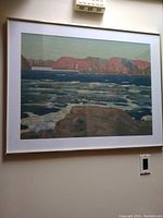 Framed landscape print showing water, ice, and red cliffs under green sky