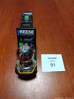 Front-facing image showing Reese Towpower hitch and ball in packaging with lot card beside it.