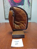 Front view of vintage baseball glove on wooden stand showing the pocket and lacing