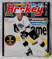 Front cover of the 1990-1991 Panini NHL hockey sticker album showing Wayne Gretzky in Los Angeles Kings uniform.