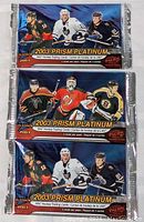 Three unopened 2003 Prism Platinum hockey card packs stacked vertically showing front packaging with NHL players