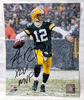 Signed 8x10 photo of Aaron Rodgers in Green Bay Packers uniform throwing a football in snow.