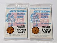 Two sealed 1st edition packs of North Carolina collegiate basketball trading cards in original plastic wrapping. Each pack contains 8 player cards.