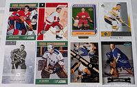 Eight hockey cards laid out, featuring star players from the past in various poses, some skating, some goalkeeping.