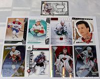 Photo of nine hockey cards arranged on a surface including a jersey patch card, several numbered cards, autographs, and rookie cards.