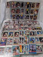 Overview of the sports cards including baseball cards in front and basketball cards behind, arranged on a white surface.