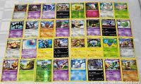 Top-down photo showing the full collection of 32 Pokemon cards laid out in a grid on a surface. The photo highlights the mix of card types and some foil cards visible under reflection.