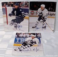 Three 8x10 Toronto Maple Leafs hockey player photos, showing players in action in both navy and white uniforms with clear blue ink autographs.